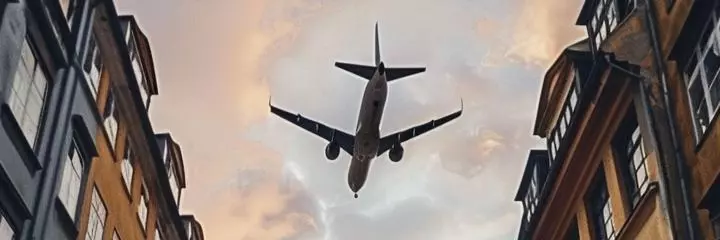 The plane flies over the city between houses